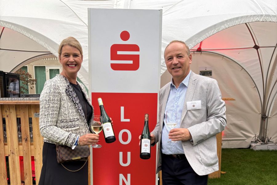 Eine Frau und ein Mann stehen mit jeweils einer Flasche Wein vor der S-Lounge. Quelle: SVN