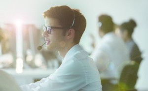 Junger Mann mit Headset im Großraumbüro. - Quelle: DSV