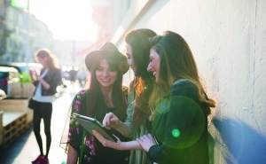 drei junge Mädchen stehen auf der Straße schauen sich etwas auf einem Tablet an. - Quelle: Image Source/Eugenio Marongiu 