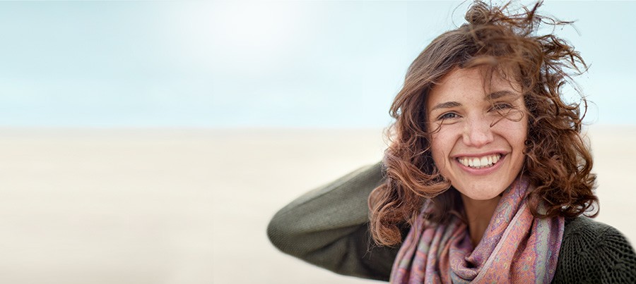 Frau mit braunen Locken am Lachen. Gutes tun